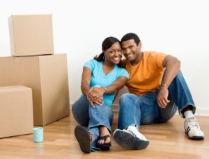 coupled seated on hardwood floor by unpacked boxes